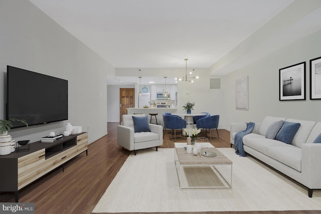 living area with a chandelier, wood finished floors, visible vents, and baseboards