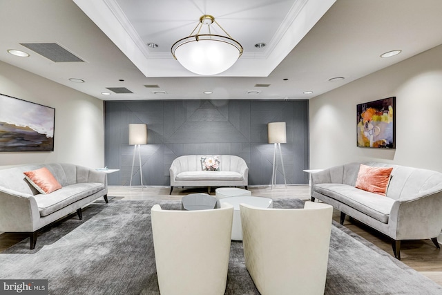 living room with recessed lighting, an accent wall, visible vents, a raised ceiling, and crown molding