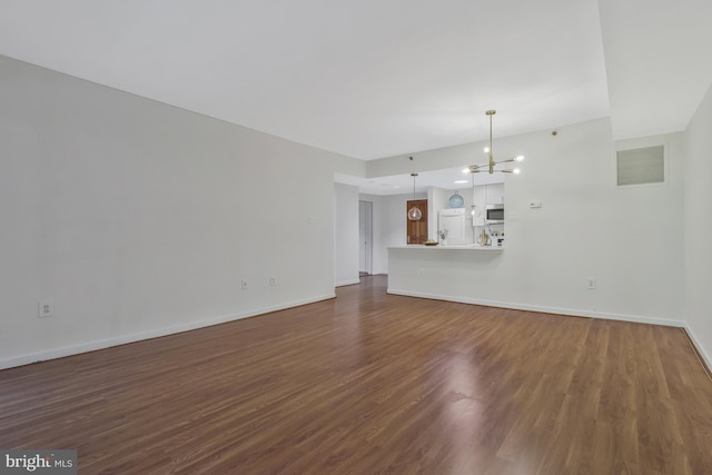 unfurnished living room featuring dark wood-type flooring, visible vents, baseboards, and an inviting chandelier