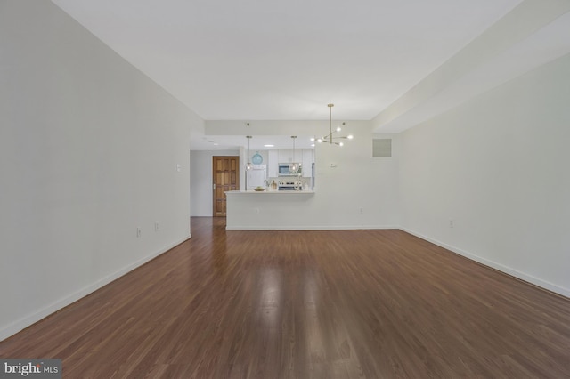 unfurnished living room featuring dark wood-style flooring, an inviting chandelier, visible vents, and baseboards