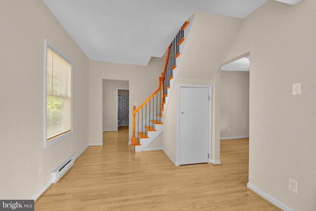 entrance foyer with light wood finished floors, a baseboard radiator, stairs, and baseboards