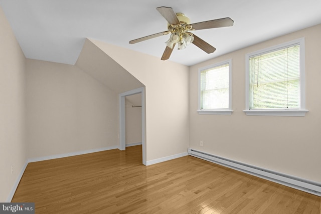 bonus room with a baseboard heating unit, light wood-style floors, baseboards, and a ceiling fan