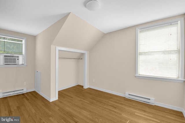 bonus room with light wood finished floors, baseboards, a baseboard heating unit, and vaulted ceiling