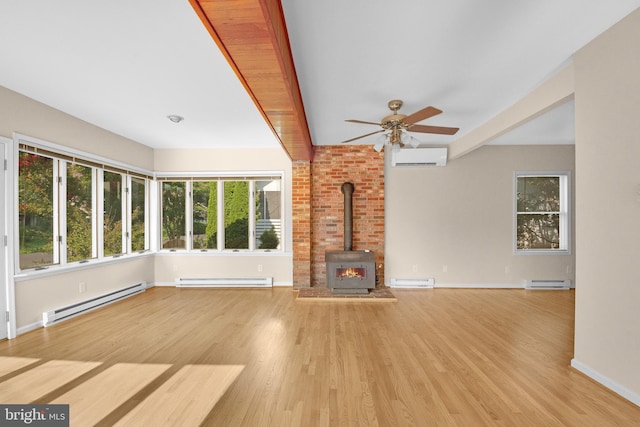 unfurnished living room featuring a wood stove, light wood-type flooring, and a baseboard heating unit