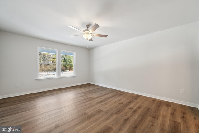 spare room with dark wood-style floors, visible vents, ceiling fan, and baseboards