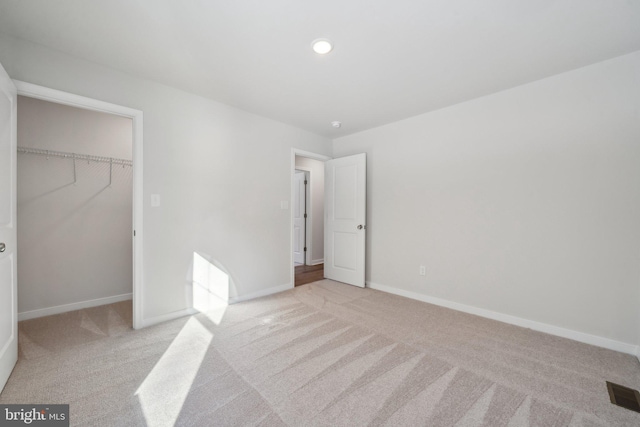 unfurnished bedroom featuring baseboards, a closet, visible vents, and light colored carpet