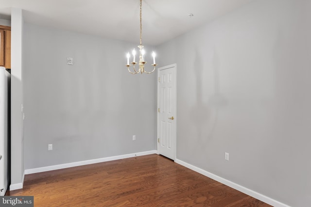 unfurnished dining area with baseboards, dark wood finished floors, and a notable chandelier