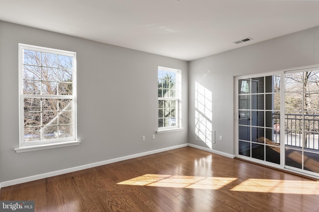 unfurnished room with wood finished floors, visible vents, and baseboards