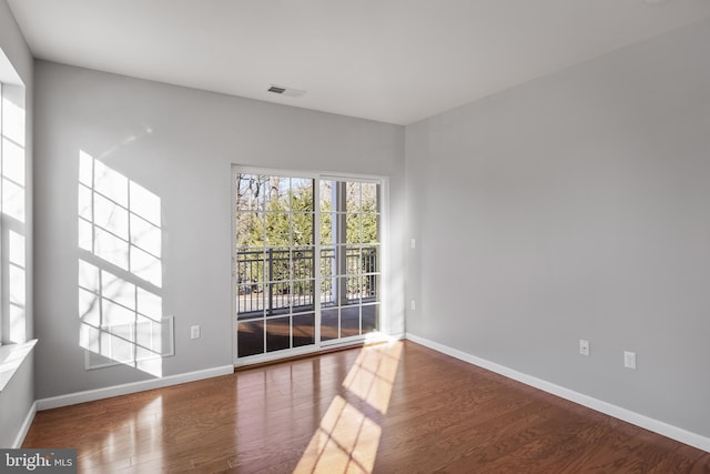 unfurnished room featuring baseboards, visible vents, and wood finished floors