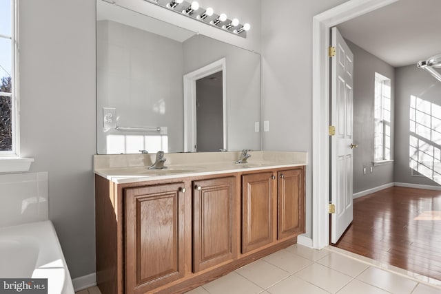 bathroom featuring tile patterned floors, double vanity, a sink, and a bath