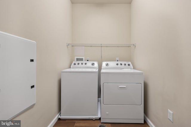 laundry room with dark wood-type flooring, washing machine and dryer, laundry area, and baseboards