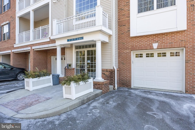 property entrance with driveway, a garage, and brick siding