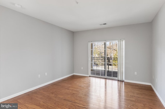 unfurnished room with baseboards, visible vents, and wood finished floors