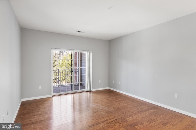 unfurnished room featuring baseboards, visible vents, and wood finished floors