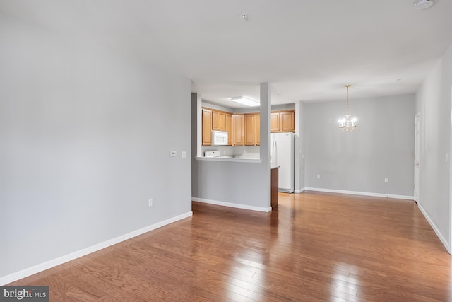 unfurnished living room featuring light wood-style floors, baseboards, and a notable chandelier