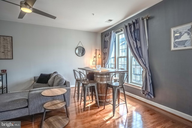 dining space with visible vents, ceiling fan, baseboards, and wood finished floors