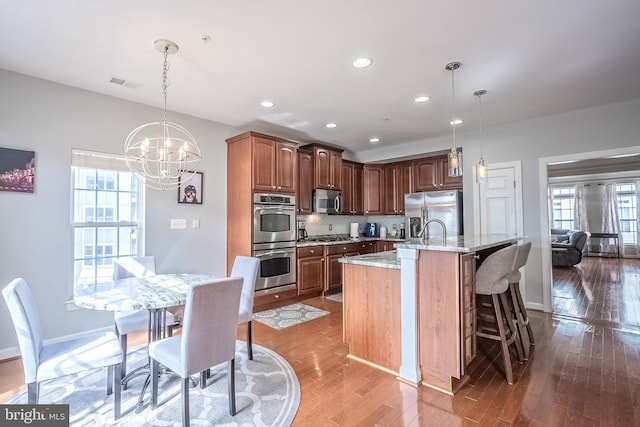 kitchen featuring an island with sink, visible vents, stainless steel appliances, and pendant lighting