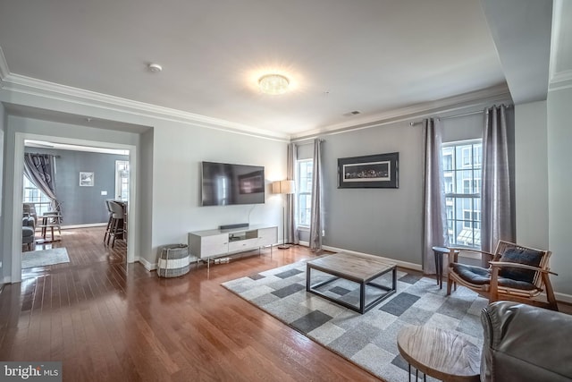 living area featuring crown molding, visible vents, baseboards, and wood finished floors