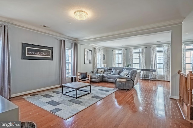 living area featuring ornamental molding, baseboards, and light wood finished floors