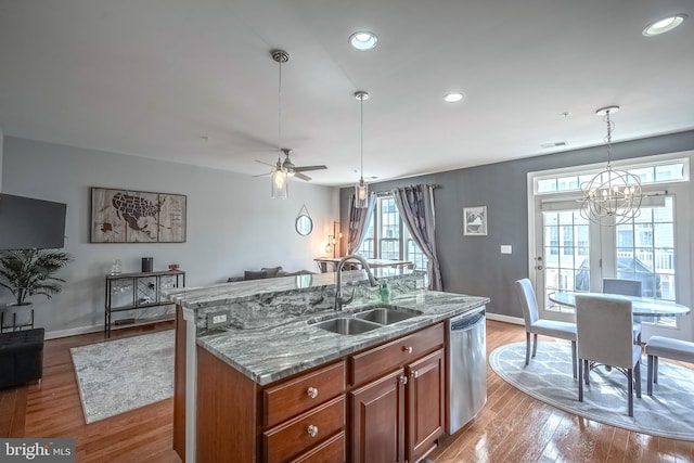 kitchen with hanging light fixtures, a center island with sink, open floor plan, and stainless steel dishwasher