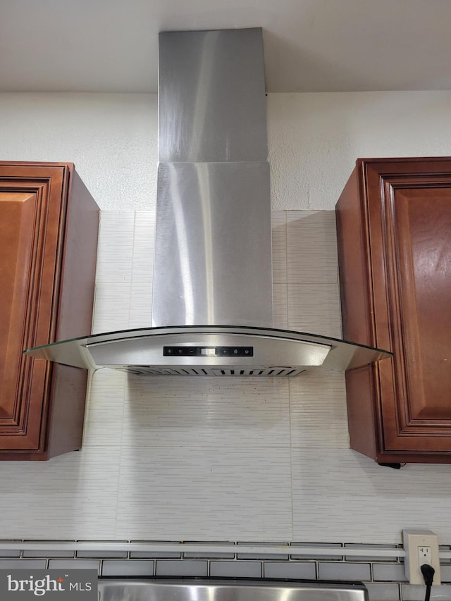 room details with brown cabinetry and wall chimney range hood