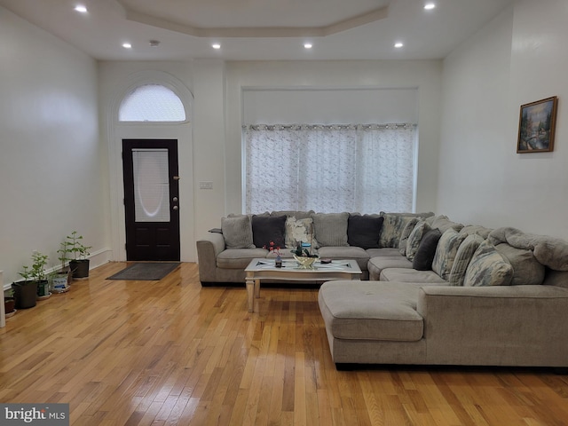 living room featuring a tray ceiling, light wood finished floors, and recessed lighting