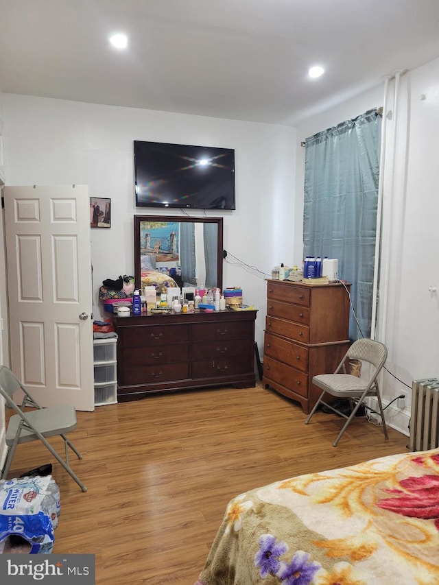 bedroom with radiator heating unit, light wood-type flooring, and recessed lighting