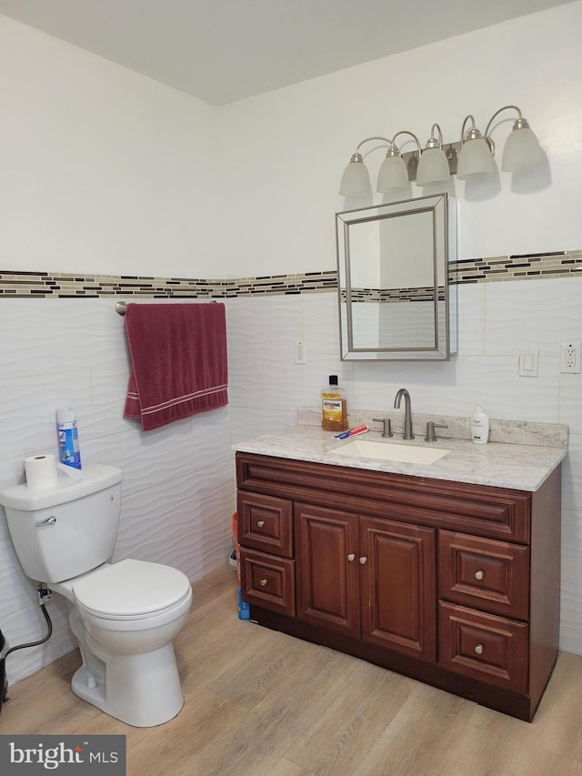 bathroom with tile walls, vanity, toilet, and wood finished floors