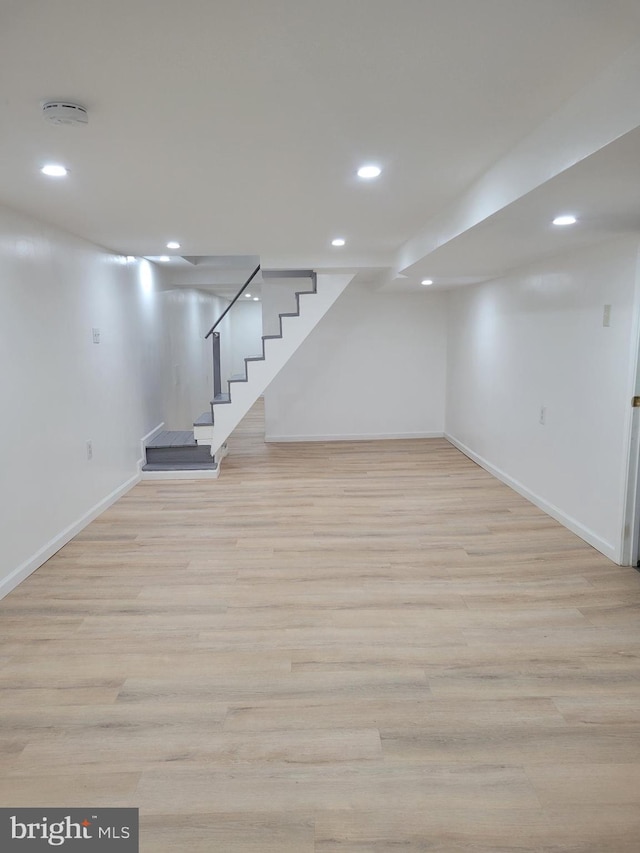 below grade area with light wood-type flooring, stairway, and recessed lighting