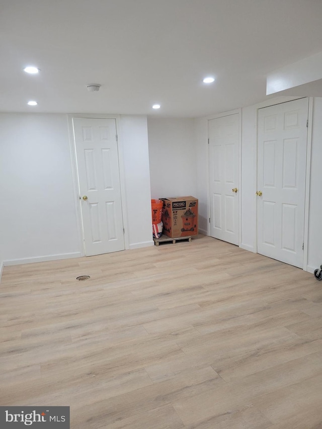 finished below grade area with light wood-type flooring, baseboards, and recessed lighting