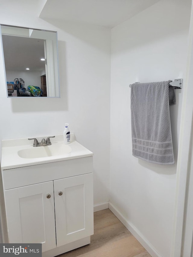 bathroom with wood finished floors, vanity, and baseboards