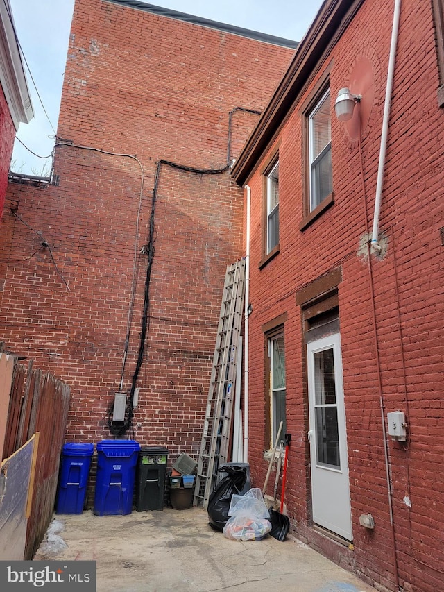 view of side of home with brick siding and fence