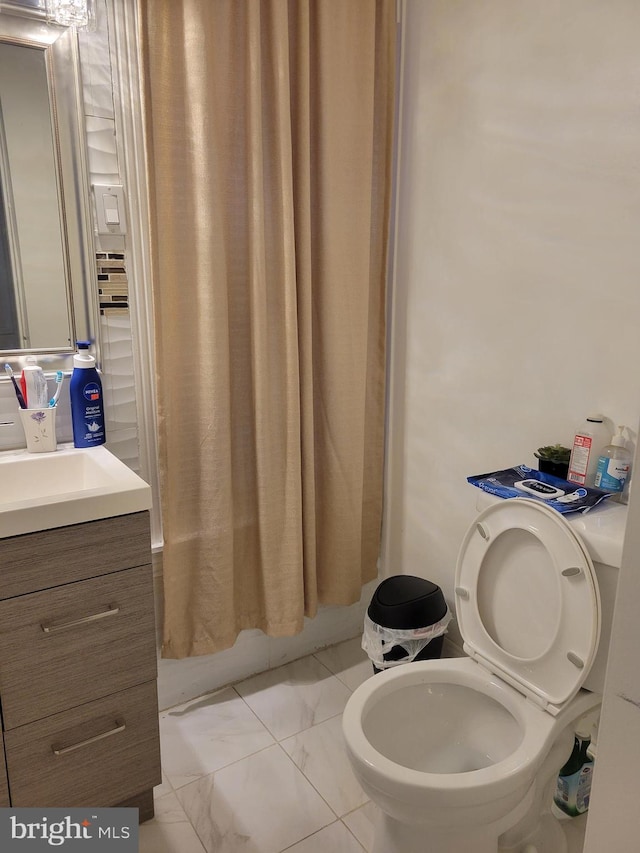 bathroom with marble finish floor, shower / tub combo with curtain, vanity, and toilet