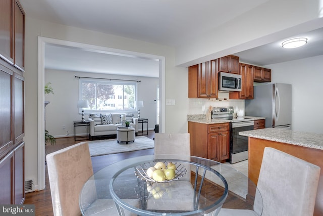 7424 Nancemond St, Springfield, VA 22150 - kitchen featuring brown cabinets, stainless steel appliances, light stone countertops, and backsplash