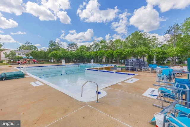 community pool with a patio area and fence