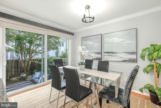 dining space with ornamental molding, wood finished floors, baseboards, and a chandelier