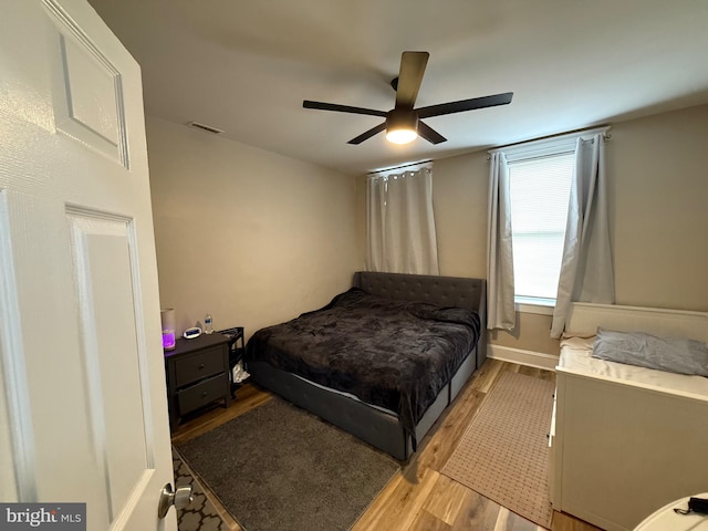 bedroom featuring light wood-style flooring, visible vents, baseboards, and ceiling fan