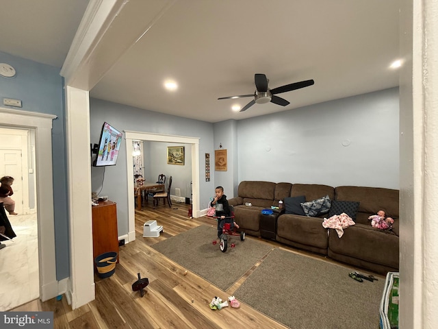 living room with ceiling fan, baseboards, and wood finished floors