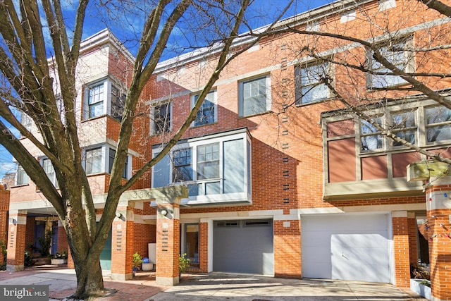 multi unit property featuring brick siding, driveway, and an attached garage