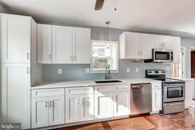 kitchen with stainless steel appliances, a sink, white cabinetry, light countertops, and light wood finished floors