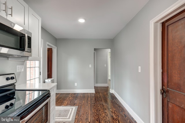 kitchen featuring white cabinets, dark wood-style floors, baseboards, and stainless steel appliances