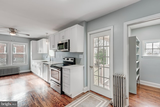 kitchen featuring light wood-type flooring, radiator heating unit, appliances with stainless steel finishes, and light countertops