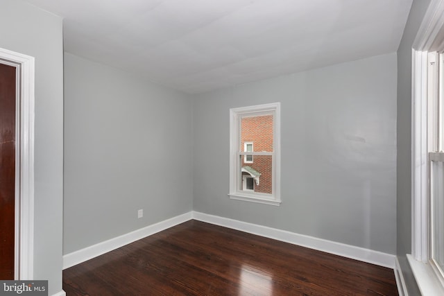 empty room with baseboards and dark wood-type flooring