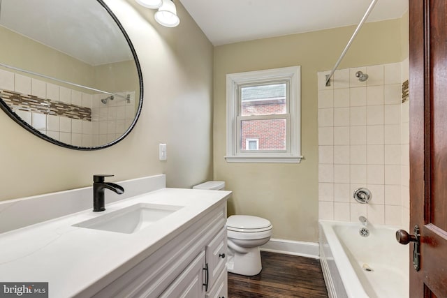 bathroom with toilet, wood finished floors, bathing tub / shower combination, vanity, and baseboards