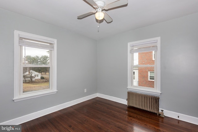 empty room featuring a healthy amount of sunlight, radiator heating unit, and dark wood-type flooring