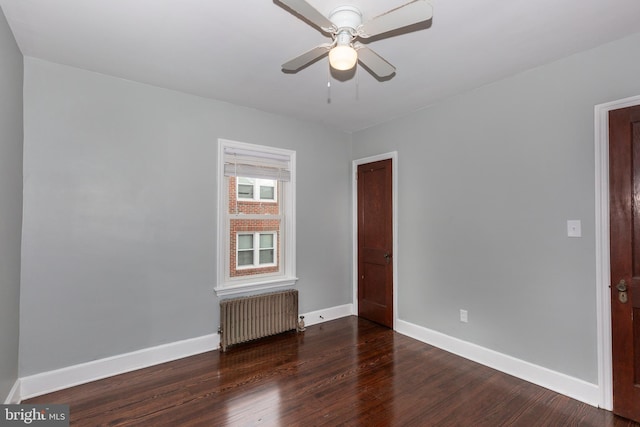 spare room featuring a ceiling fan, radiator heating unit, baseboards, and wood finished floors