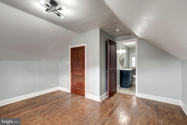 additional living space with lofted ceiling, hardwood / wood-style floors, and baseboards