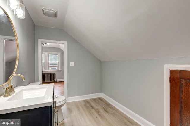 bathroom featuring baseboards, visible vents, toilet, radiator heating unit, and wood finished floors