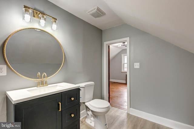 bathroom with visible vents, toilet, vaulted ceiling, vanity, and wood finished floors