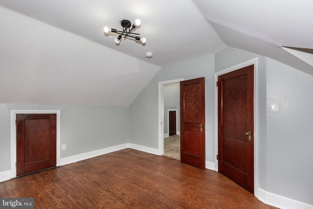 bonus room with dark wood-type flooring, vaulted ceiling, and baseboards